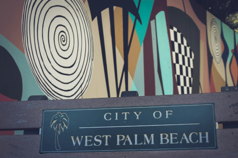 a city of west palm beach sign in front of a mural